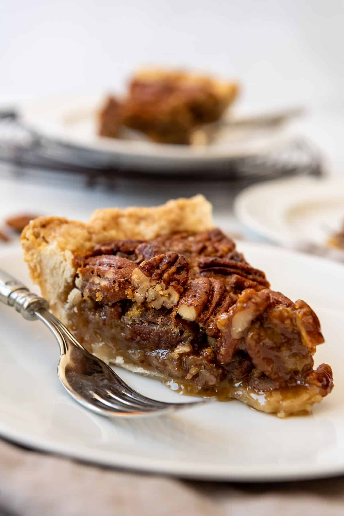 a slice of gooey pecan pie on a plate with a fork.