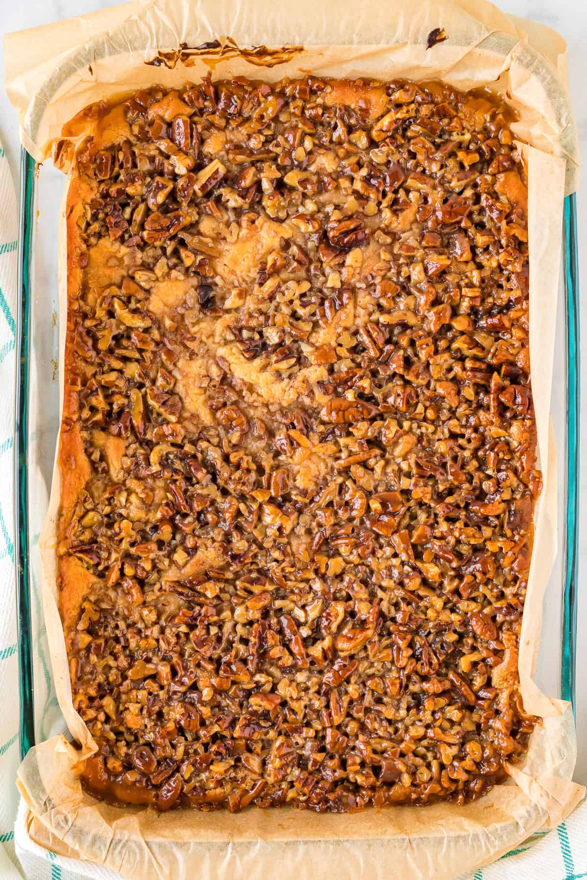 Baked pecan pie cheesecake bars in a pan before cutting into squares.