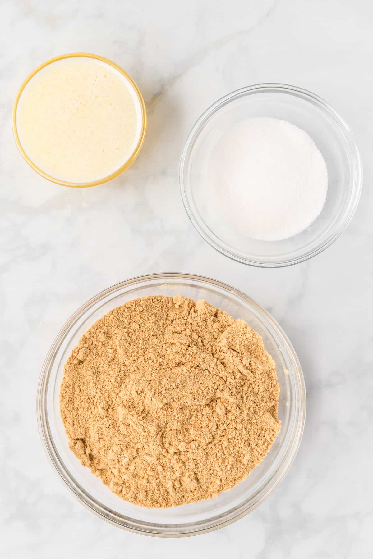 Melted butter, granulated sugar, and graham cracker crumbs in glass bowls.