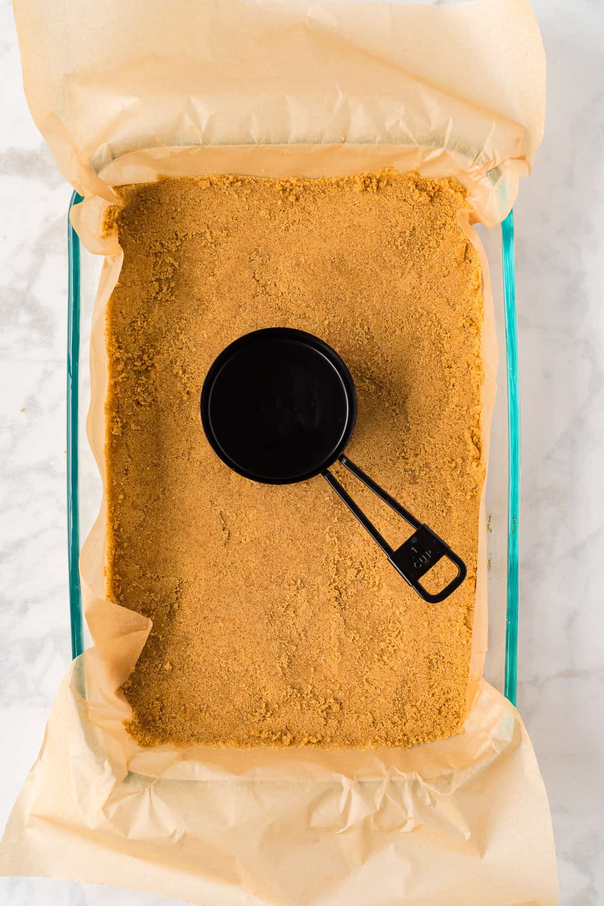 Pressing a graham cracker crust into a 9x13-inch pan.