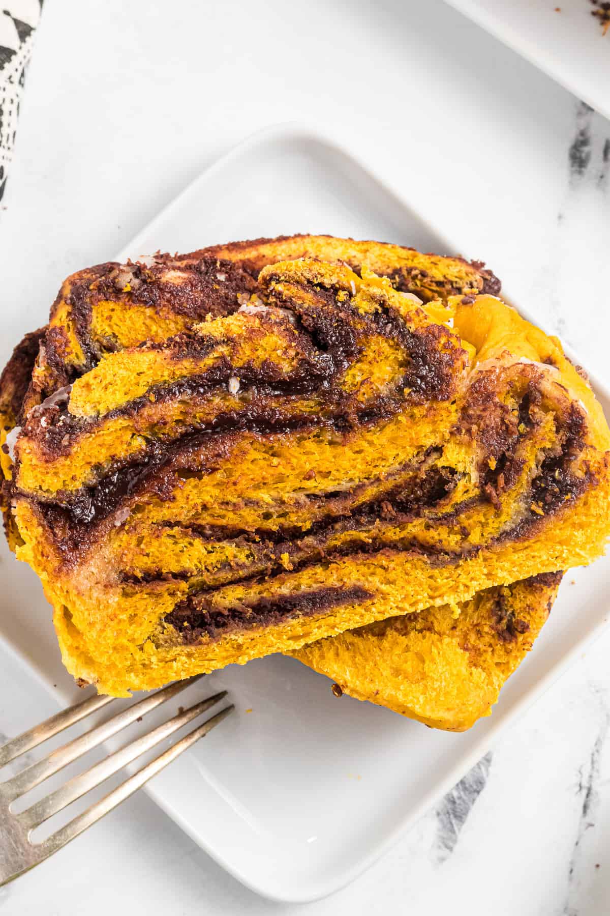 a slice of pumpkin babka swirled with chocolate filling on a white plate.