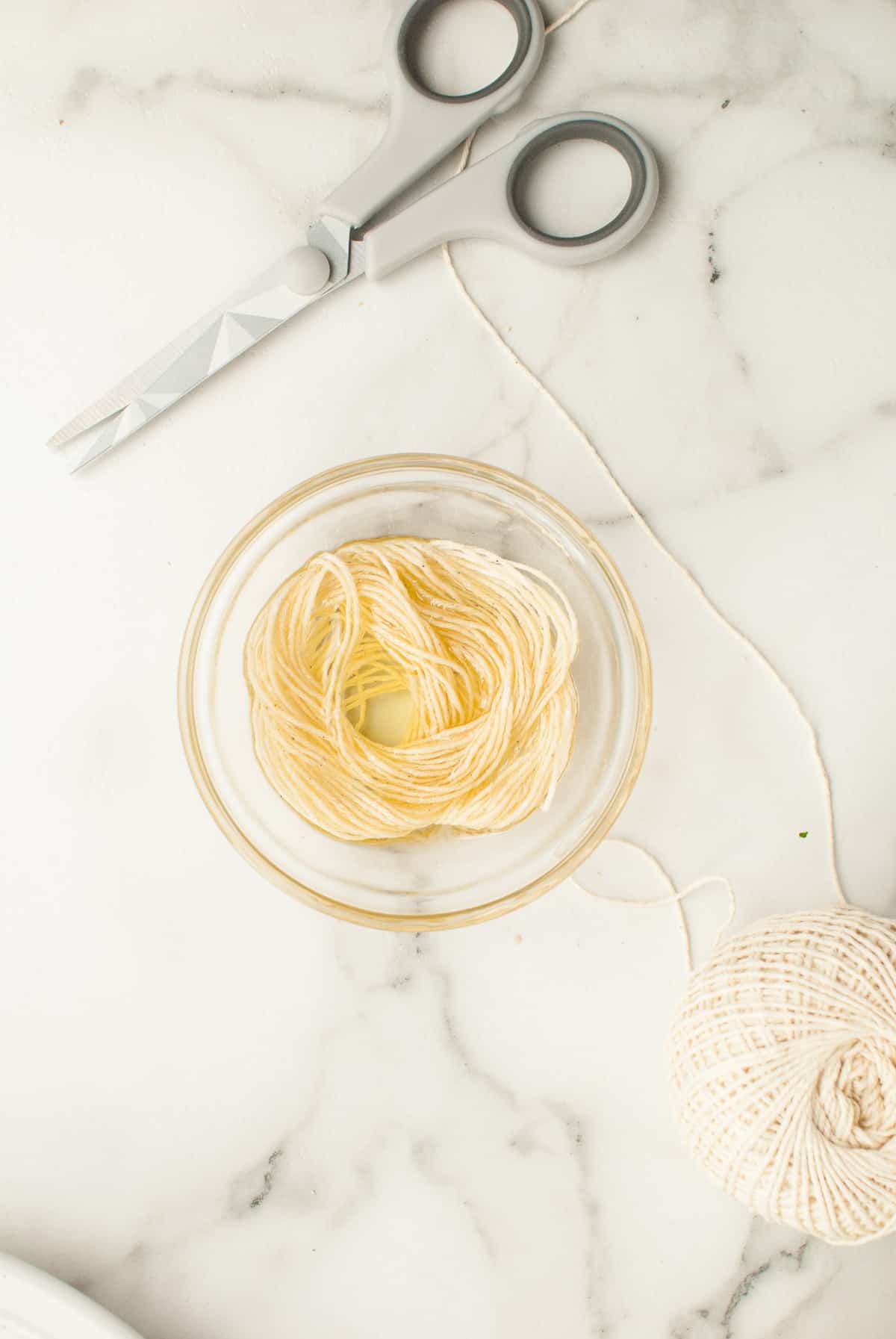 Cut kitchen twine is soaking in oil in a small bowl. 