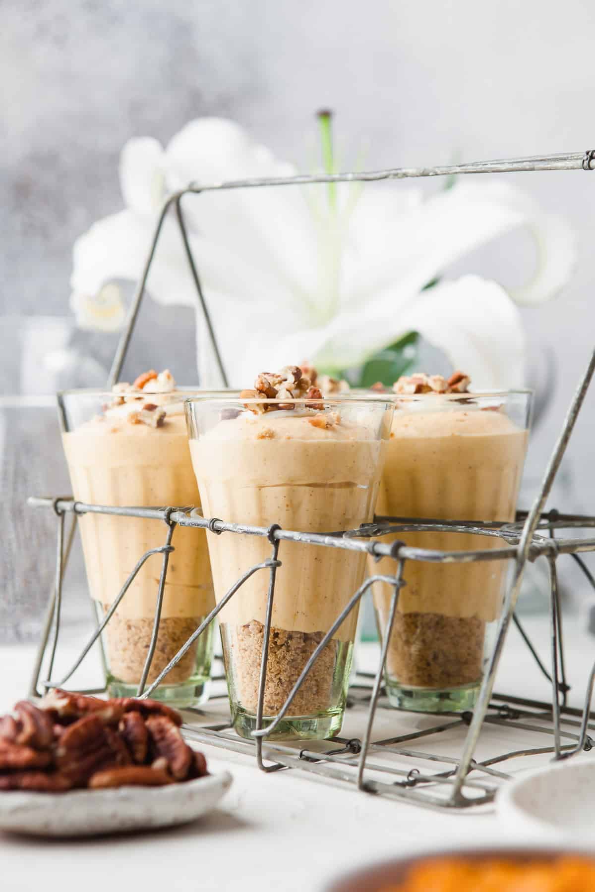 Three glass dessert cups with pumpkin cheesecake mousse over graham cracker crust.