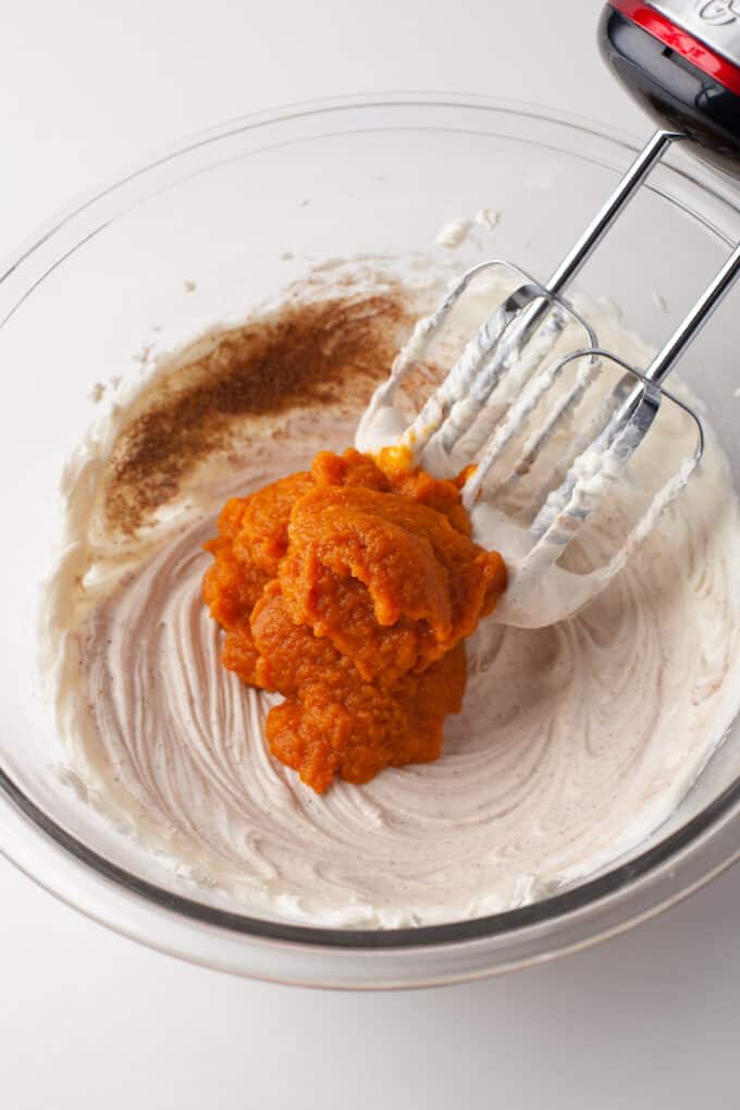 Adding pumpkin puree to a cream cheese no-bake cheesecake base.