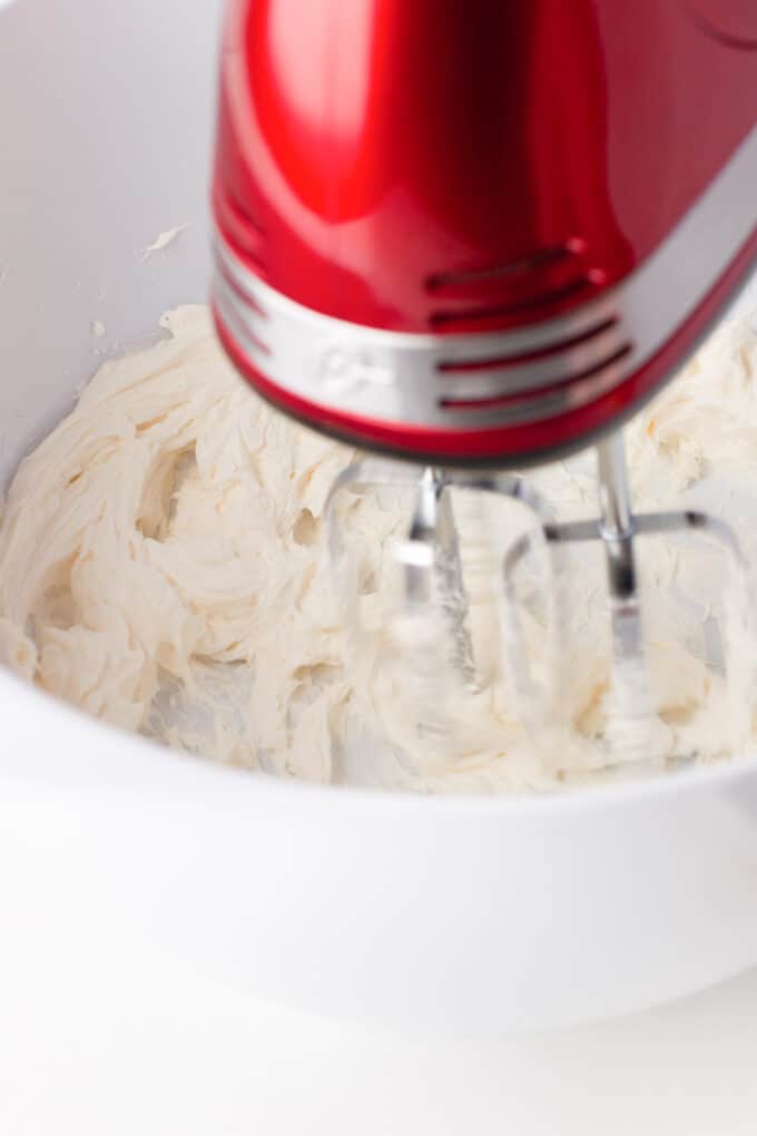 Beating cream cheese with an electric mixer.
