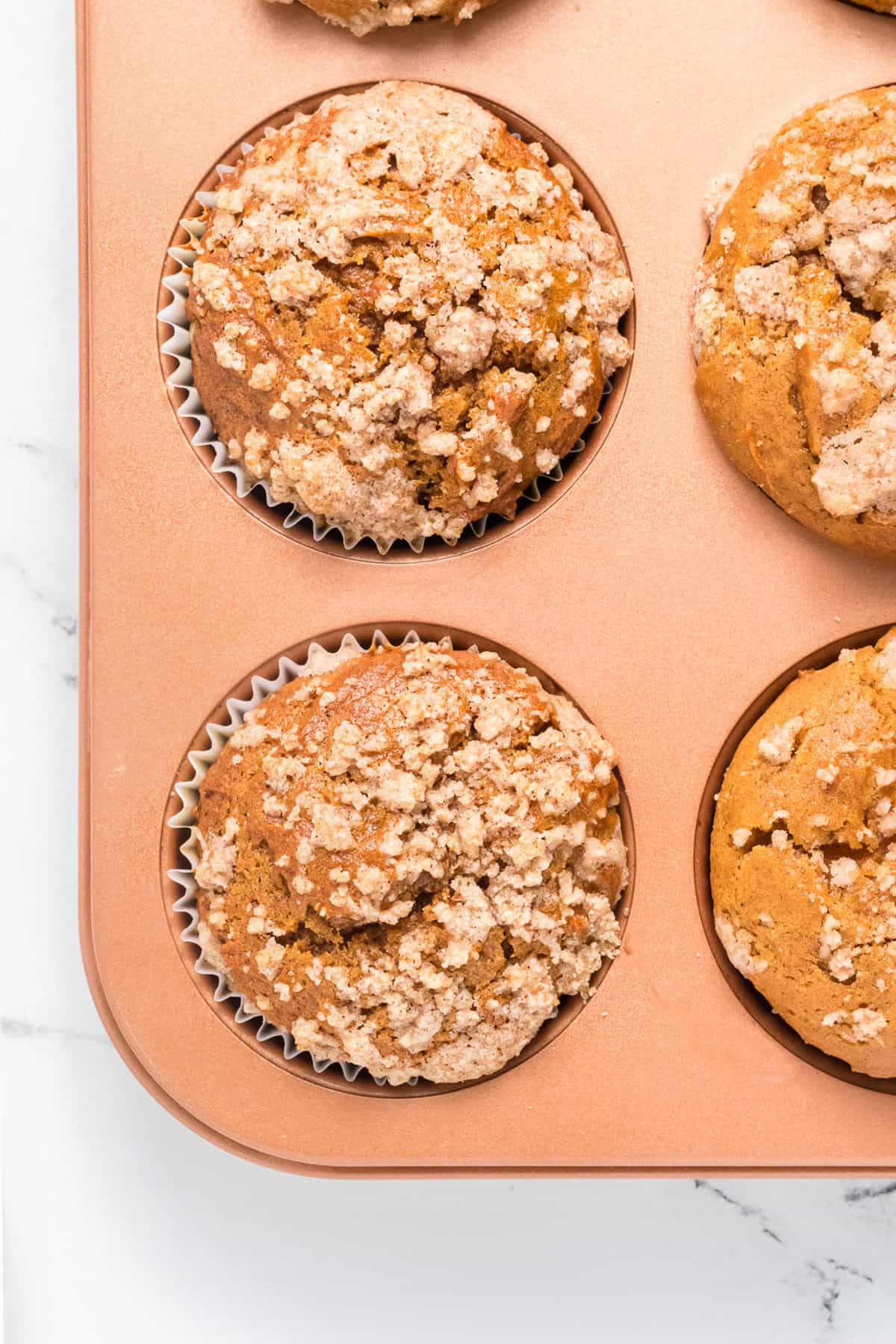 a close up image of a pumpkin muffin with streusel topping.