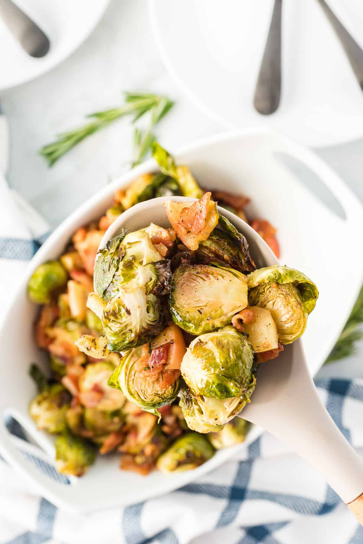 A serving spoon holding a large scoop of roasted brussels sprouts.