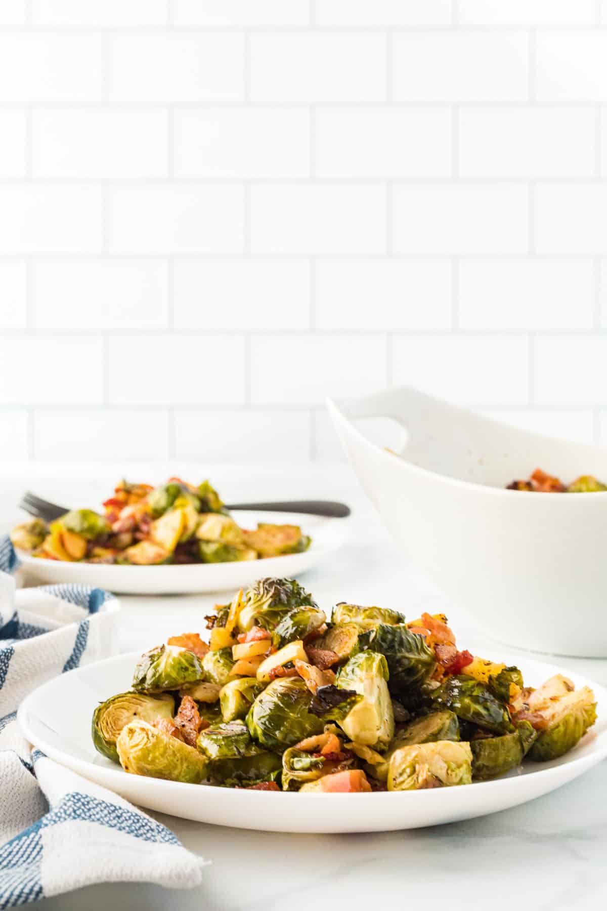 A white plate with a pile of roasted brussels sprouts with bacon on it.