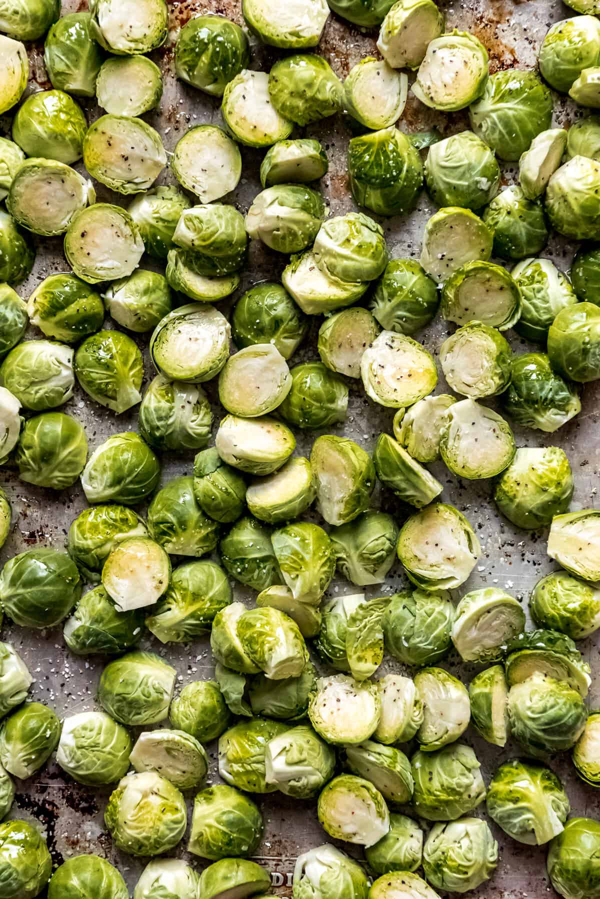 Brussels sprouts that have been sliced in half on a baking sheet lined with parchment paper.