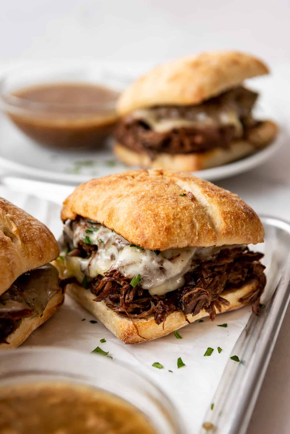 a shredded beef sandwich with melted cheese on a ciabatta bun.