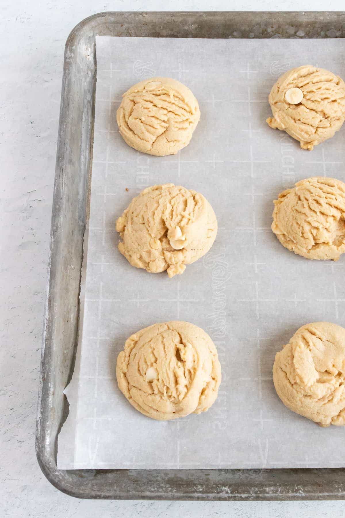 Peanut butter white chocolate cookies are baked and resting on a baking sheet. 