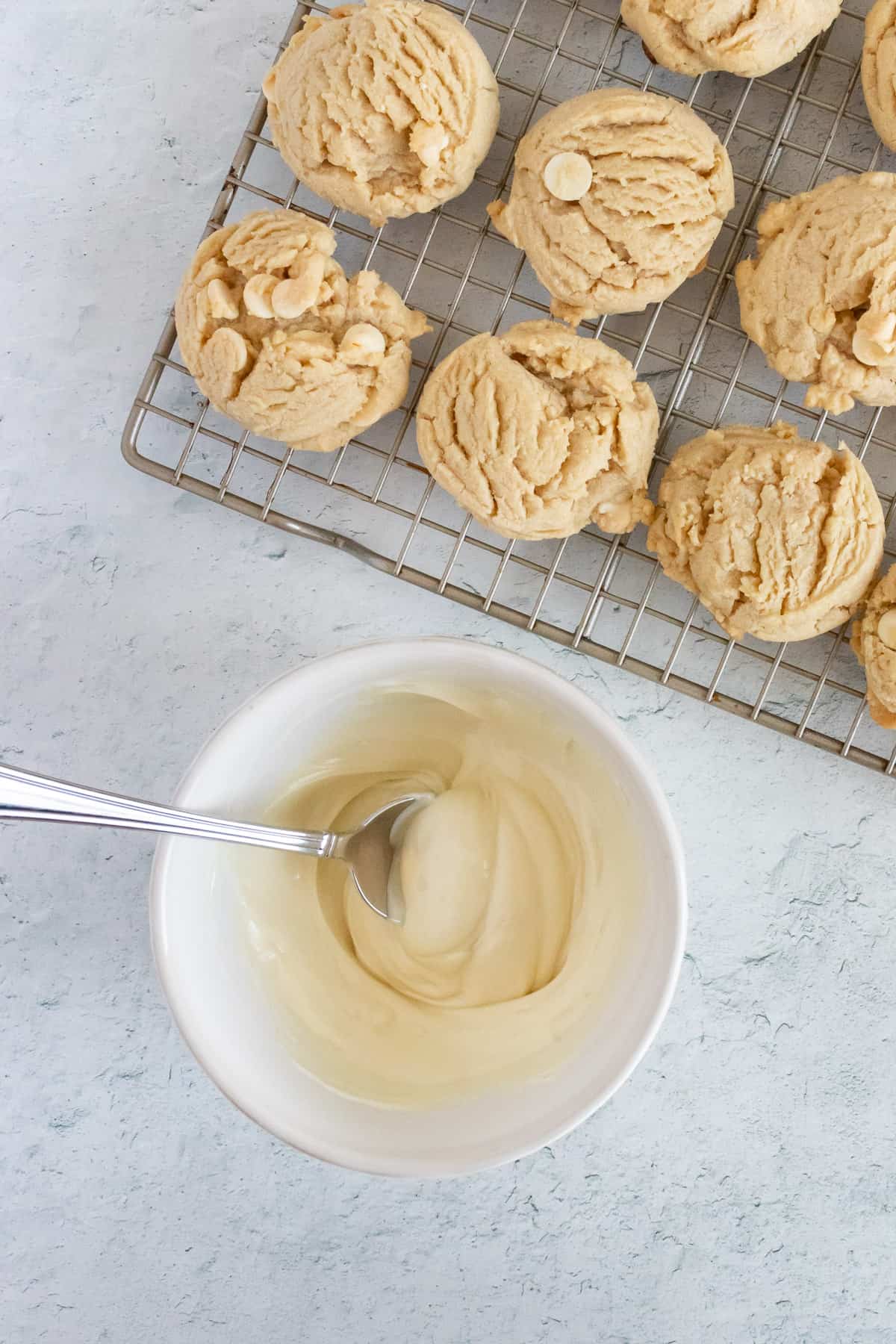 Peanut butter cookies are resting on a wire rack and ready to be dipped in white chocolate. 