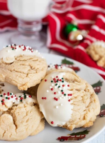 Peanut butter cookies with white chocolate chips and holiday sprinkles on a plate.