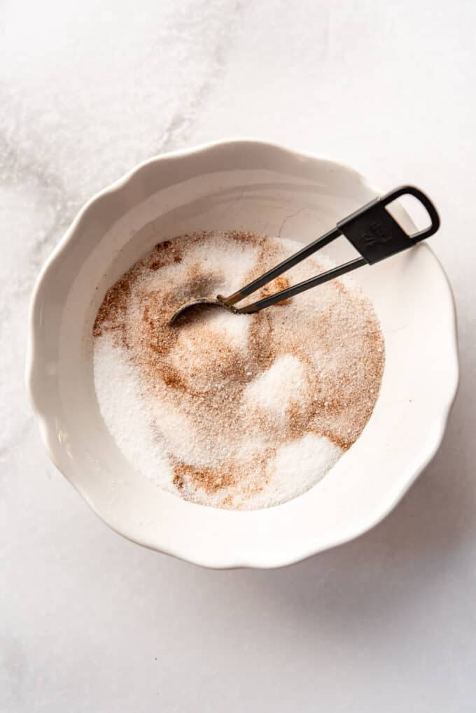 cinnamon and sugar being stirred together in a white bowl.