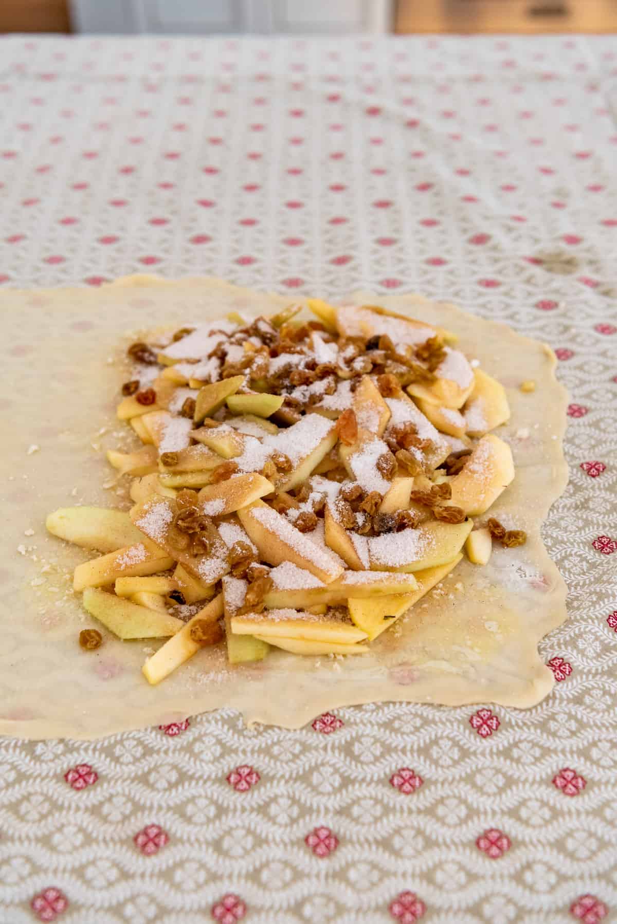 thinly sliced apples sprinkled with cinnamon, sugar, and raisins on a thin pastry dough.