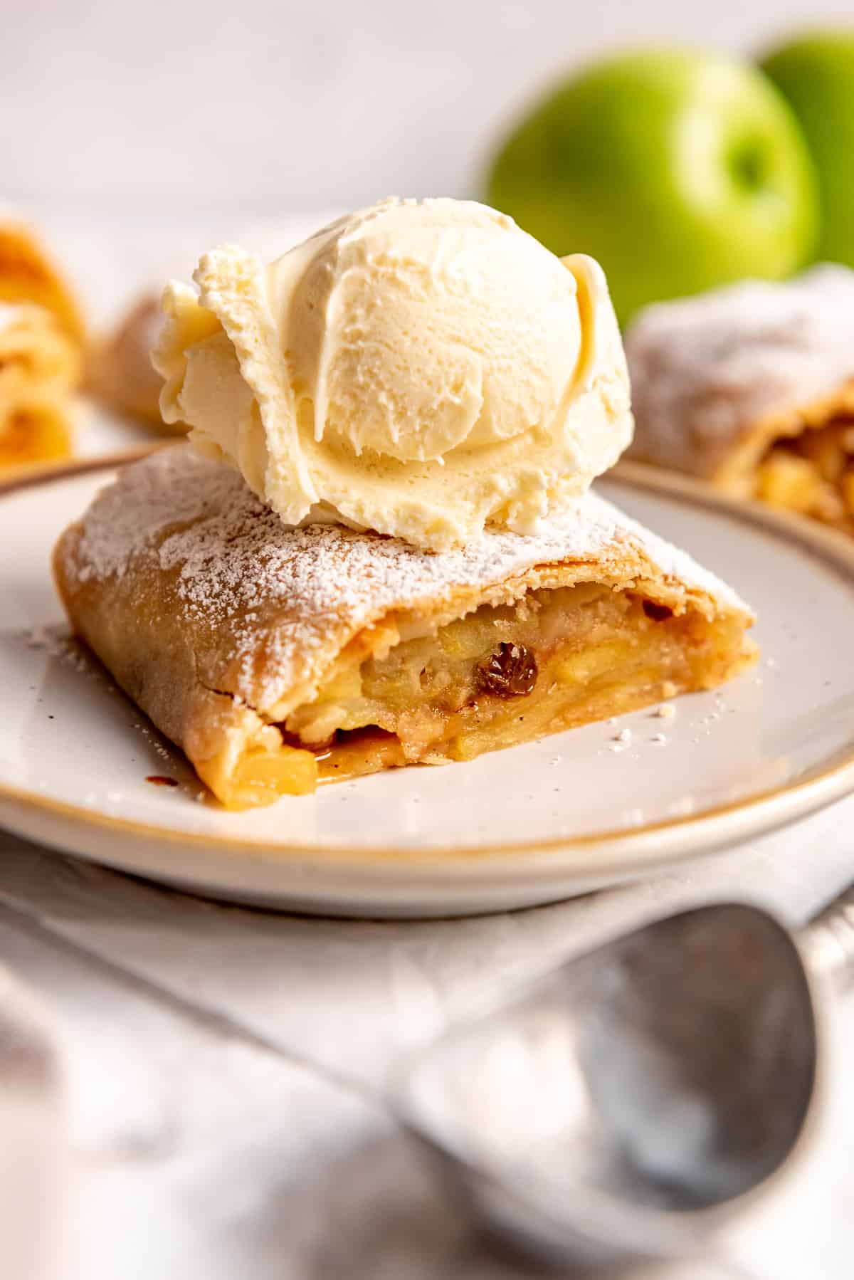 a slice of apple strudel with a scoop of vanilla ice cream on top on a plate.