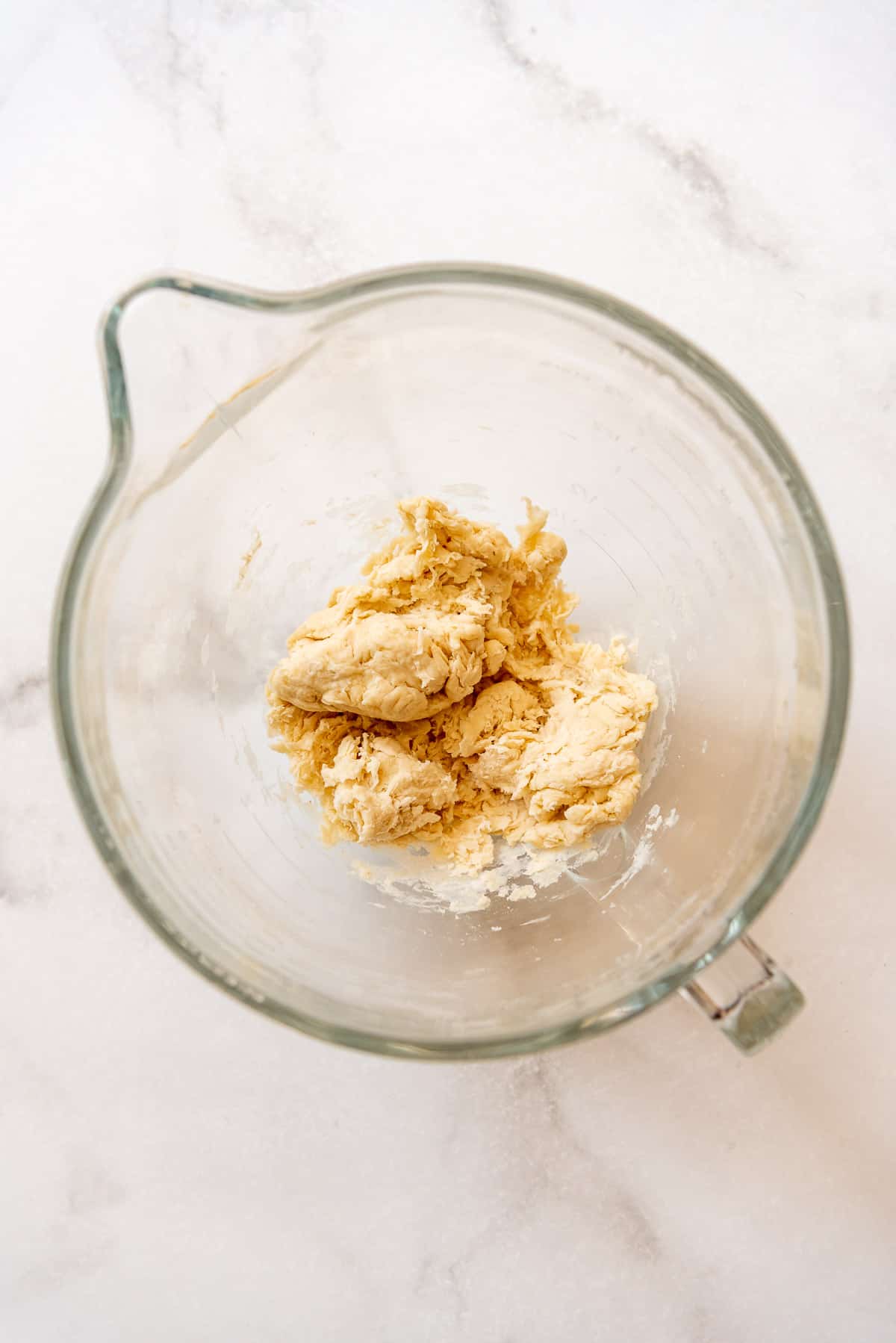 a shaggy dough coming together in a glass bowl.