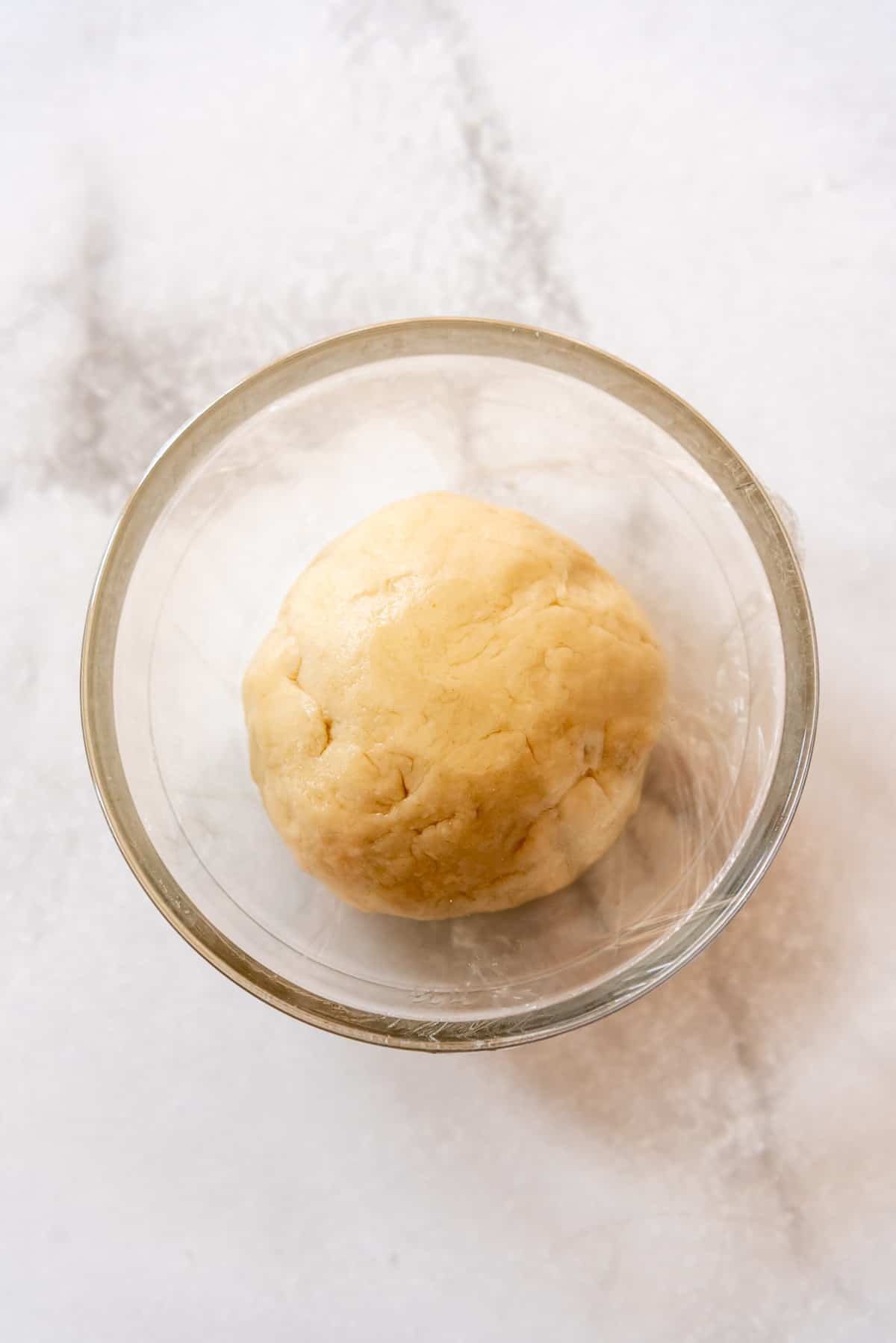 strudel dough in a glass bowl covered with plastic wrap while it rests so the gluten can relax.