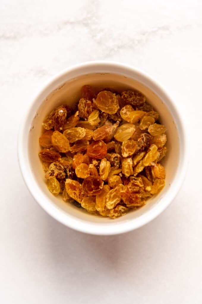 golden raisins soaking in a bowl of hot water to plump.
