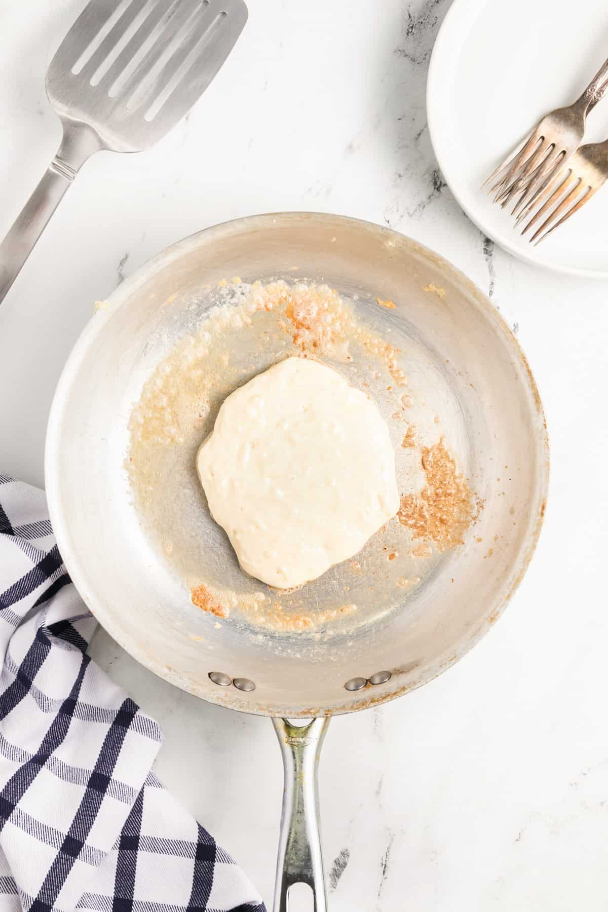 Pancake butter cooking in a buttered skillet before flipping.