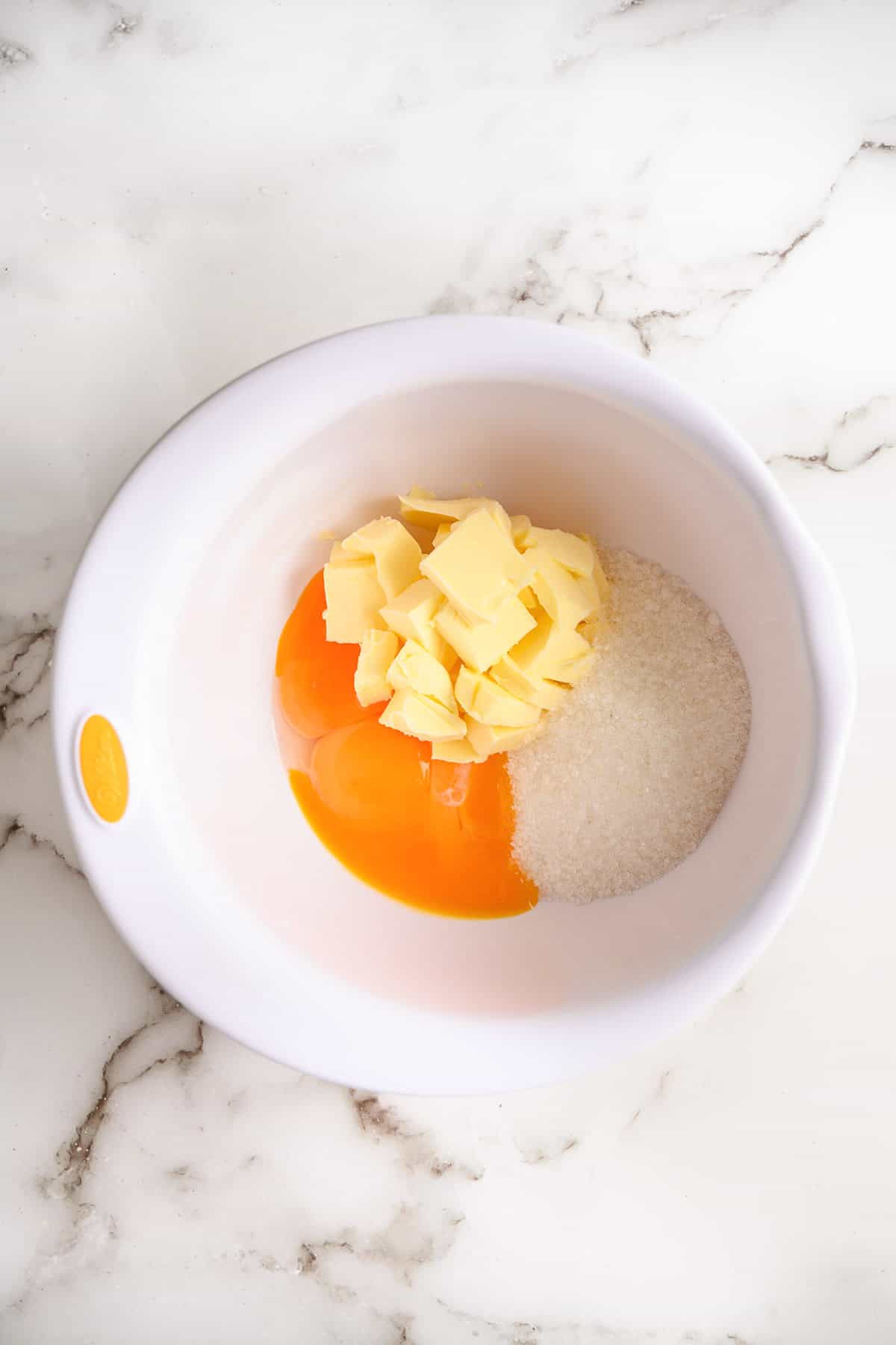 Combining eggs, sugar, and butter in a bowl.