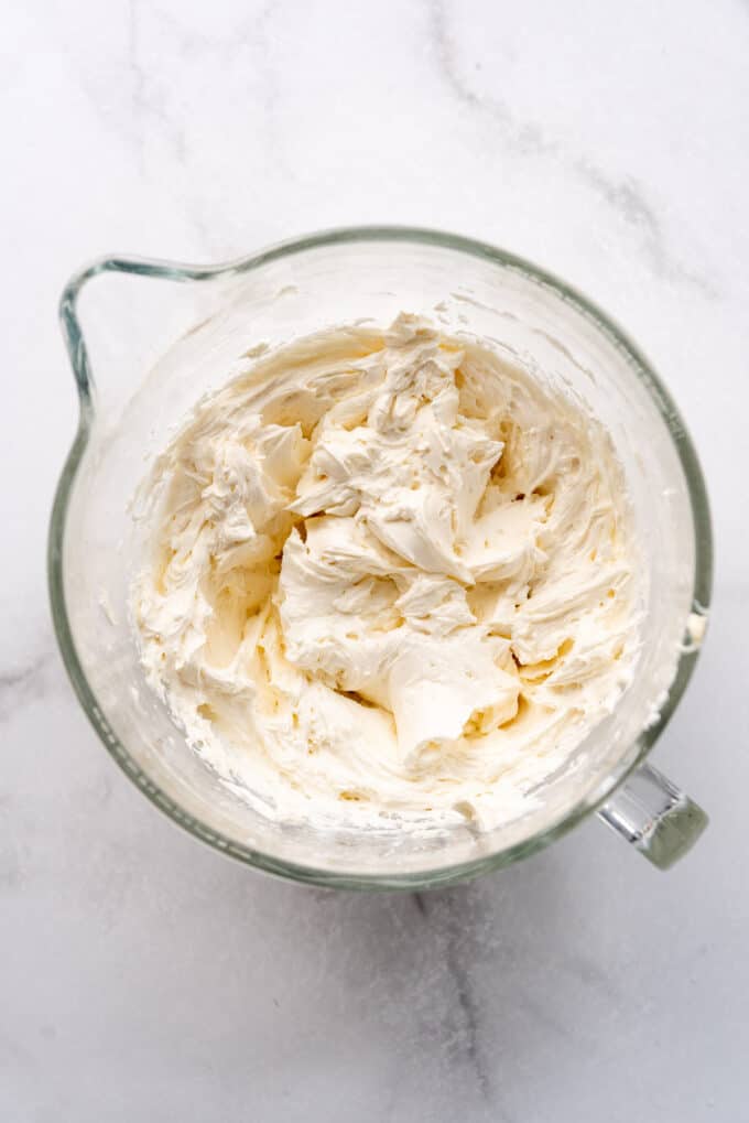 Fluffy vanilla buttercream frosting in a large glass mixing bowl.