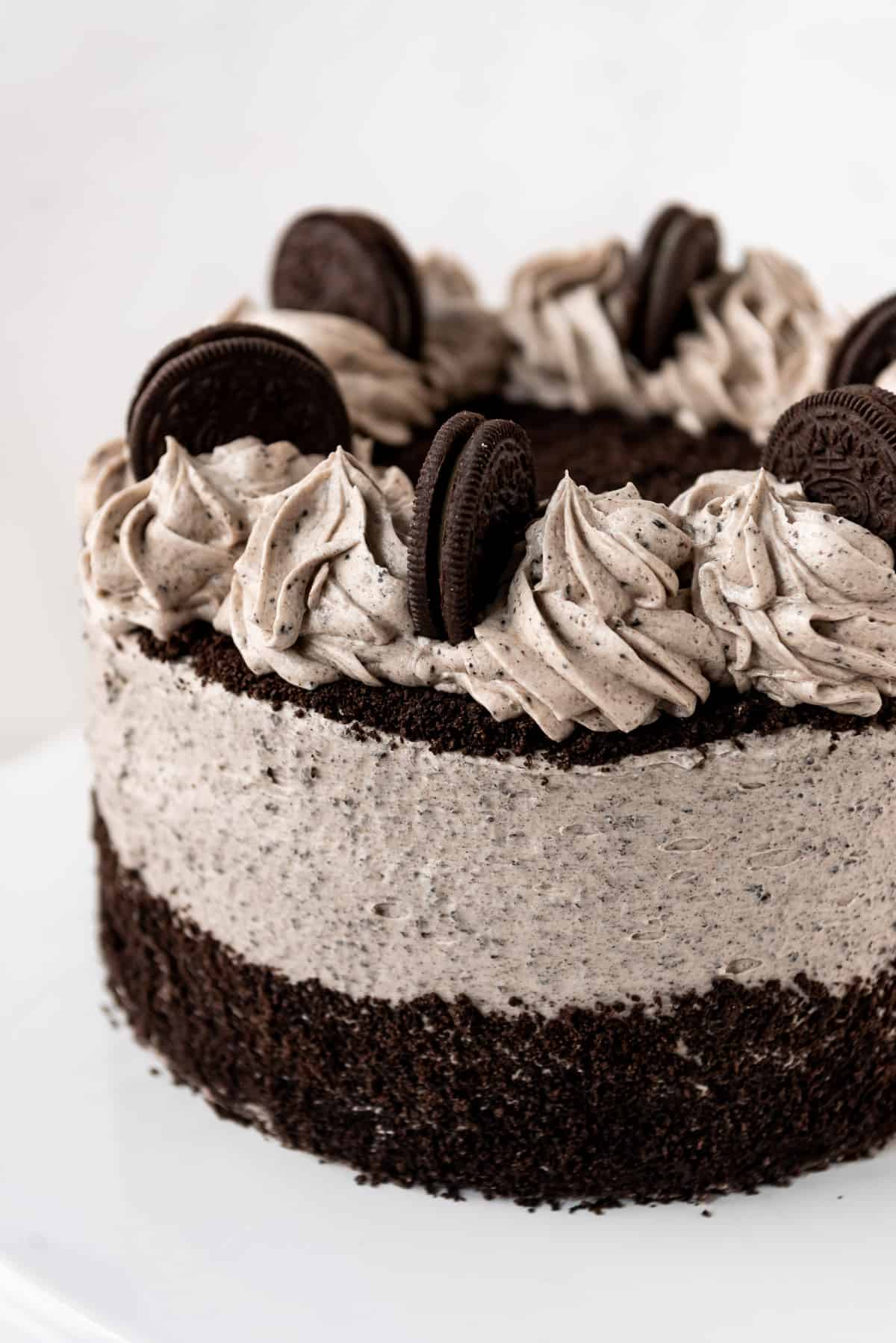 A cookies and cream cake decorated with swirls of Oreo frosting and finely crushed Oreo cookies.