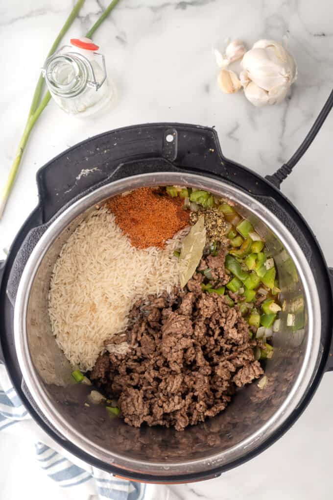 Adding dirty rice ingredients to an instant pot.