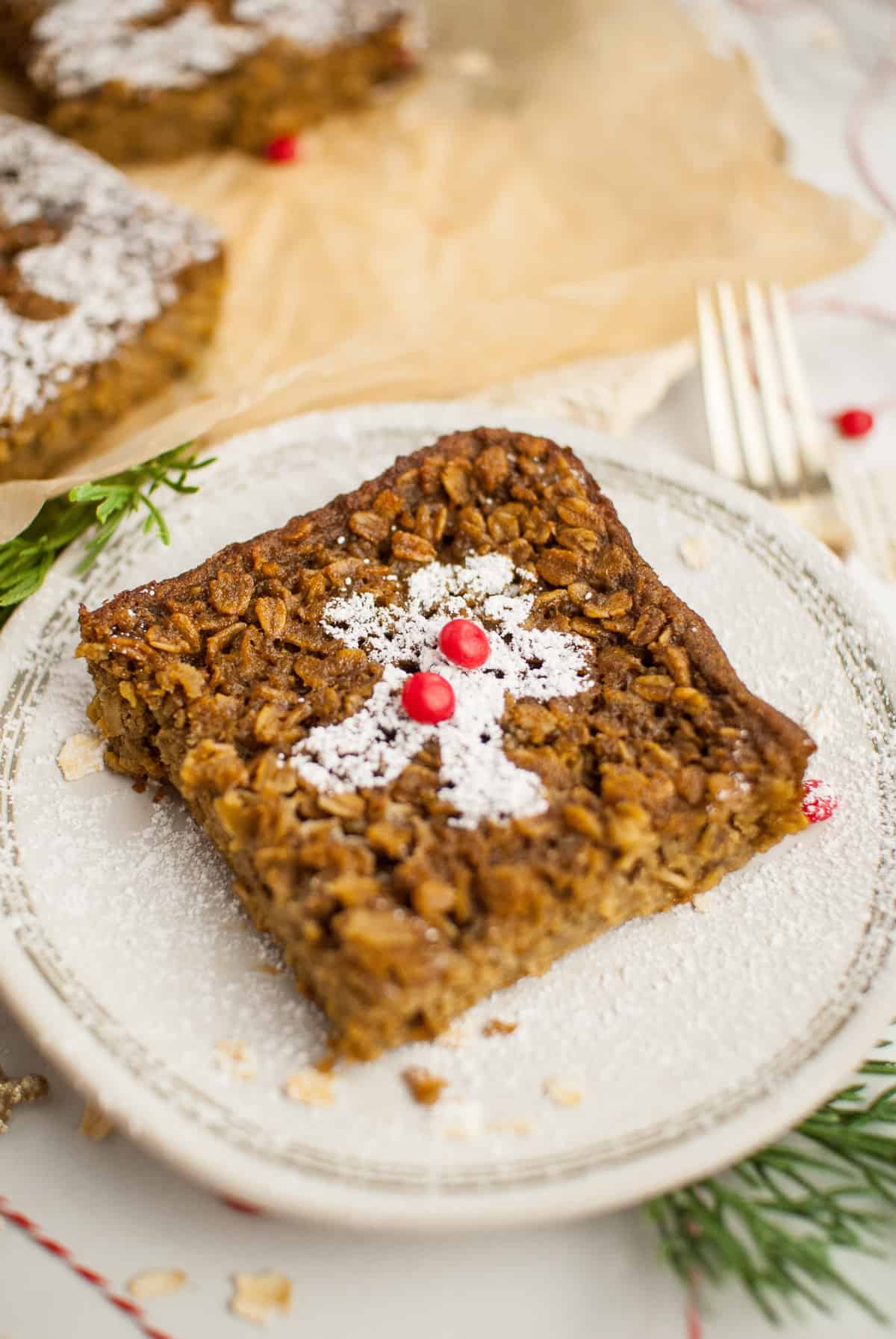 A gingerbread baked oatmeal square on a plate, with a fork and other squares visible in the background. 