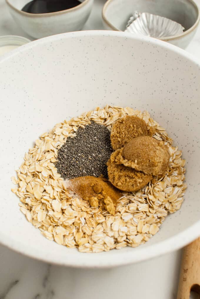 Rolled oats, brown sugar, cinnamon, and chia seeds in a large bowl.