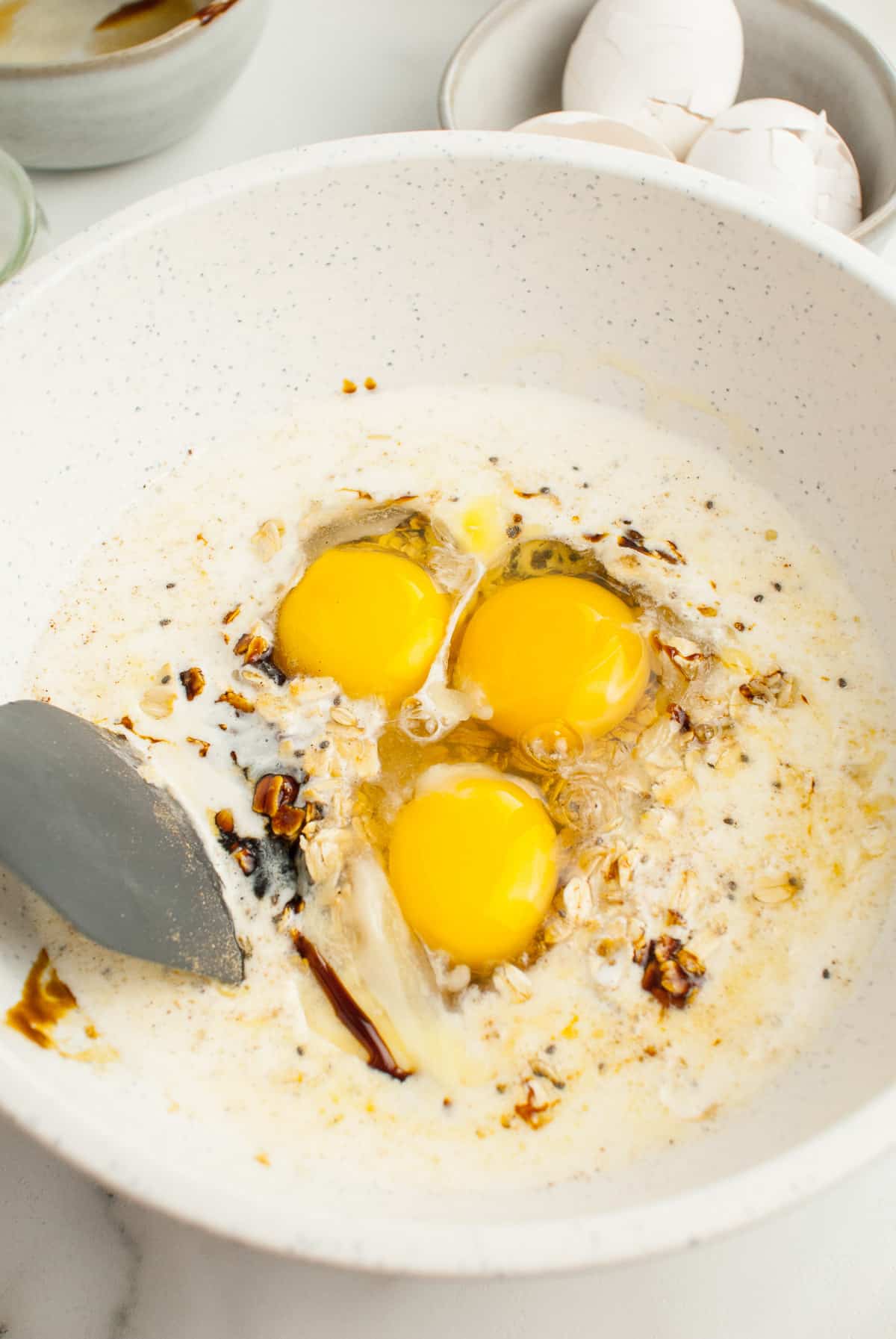 Adding eggs, and milk to oatmeal and spices for baked oatmeal.