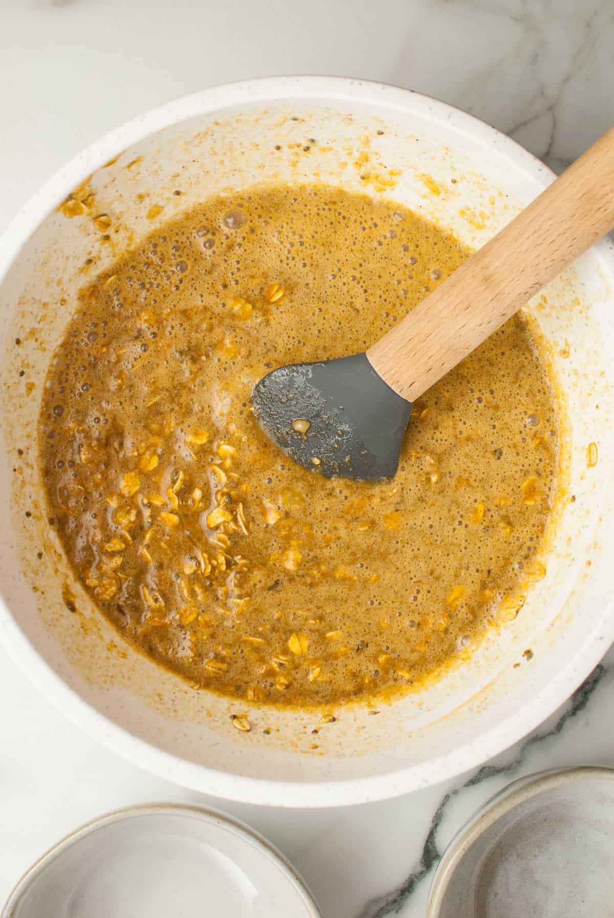 A bowl of oats with cream, water, molasses, eggs, and spices ready to be poured into a pan and baked.