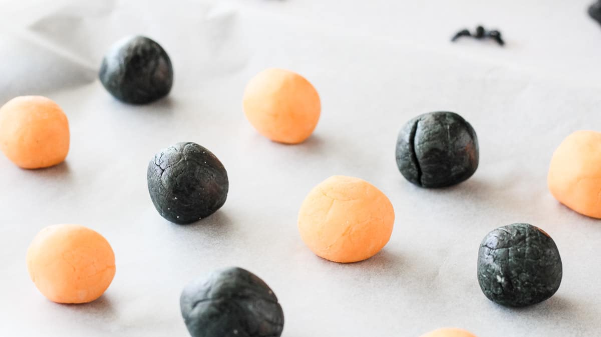 Round orange and black cream cheese mint balls ready to be pressed into shapes.