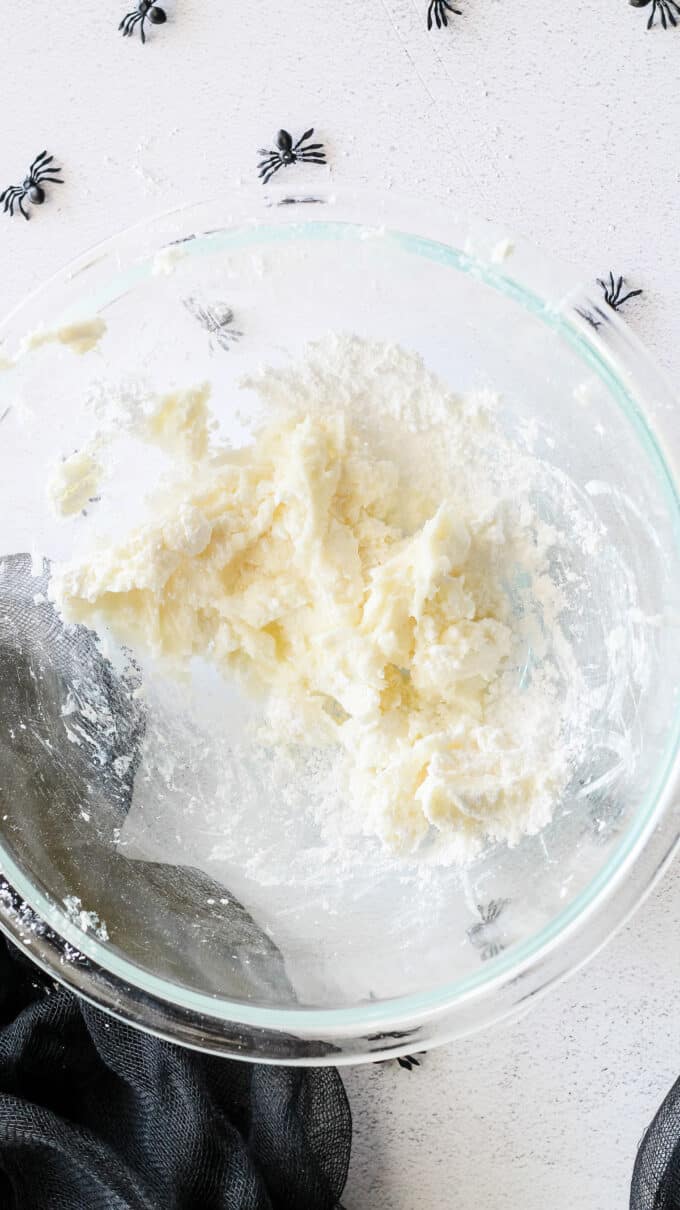 mixing cream cheese and powdered sugar together in a glass bowl.