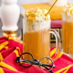 A mug of homemade butterbeer with round Harry Potter glasses in front of it.