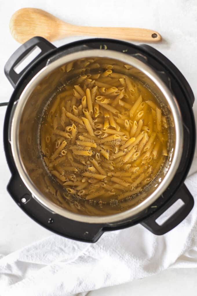 Adding liquid to penne pasta in an instant pot.