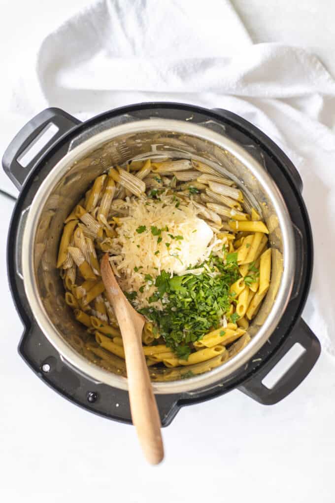 Adding cream, parmesan cheese, cream cheese, and herbs to pasta in the instant pot.