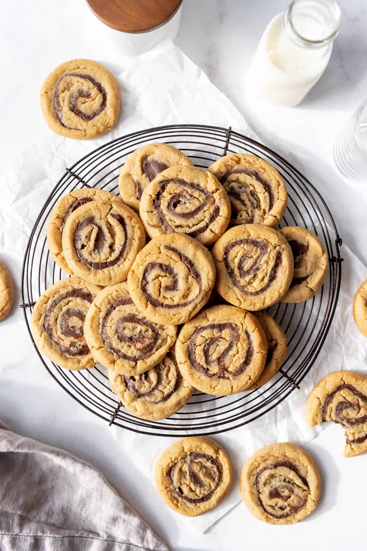 Swirls of chocolate filling in peanut butter cookies arranged on a cooling rack over parchment paper.