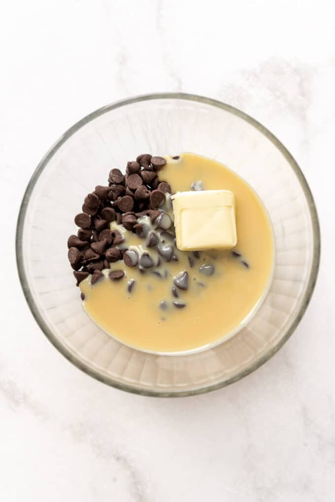 Butter, chocolate chips, and sweetened condensed milk in a glass bowl.