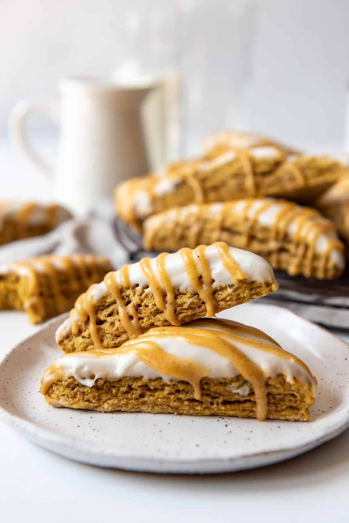 Two copycat Starbucks pumpkin scones on a plate with more behind them.