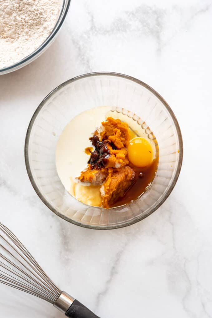 Pumpkin, heavy cream, egg, molasses, and vanilla in a glass bowl.