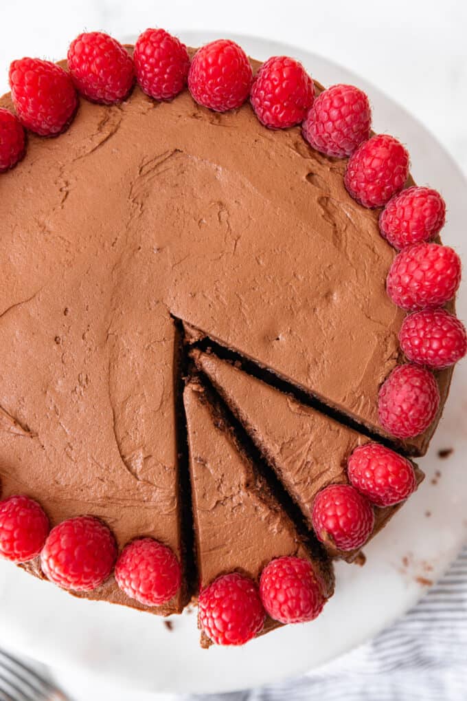 Two slices cut into a chocolate cake topped with fresh raspberries.