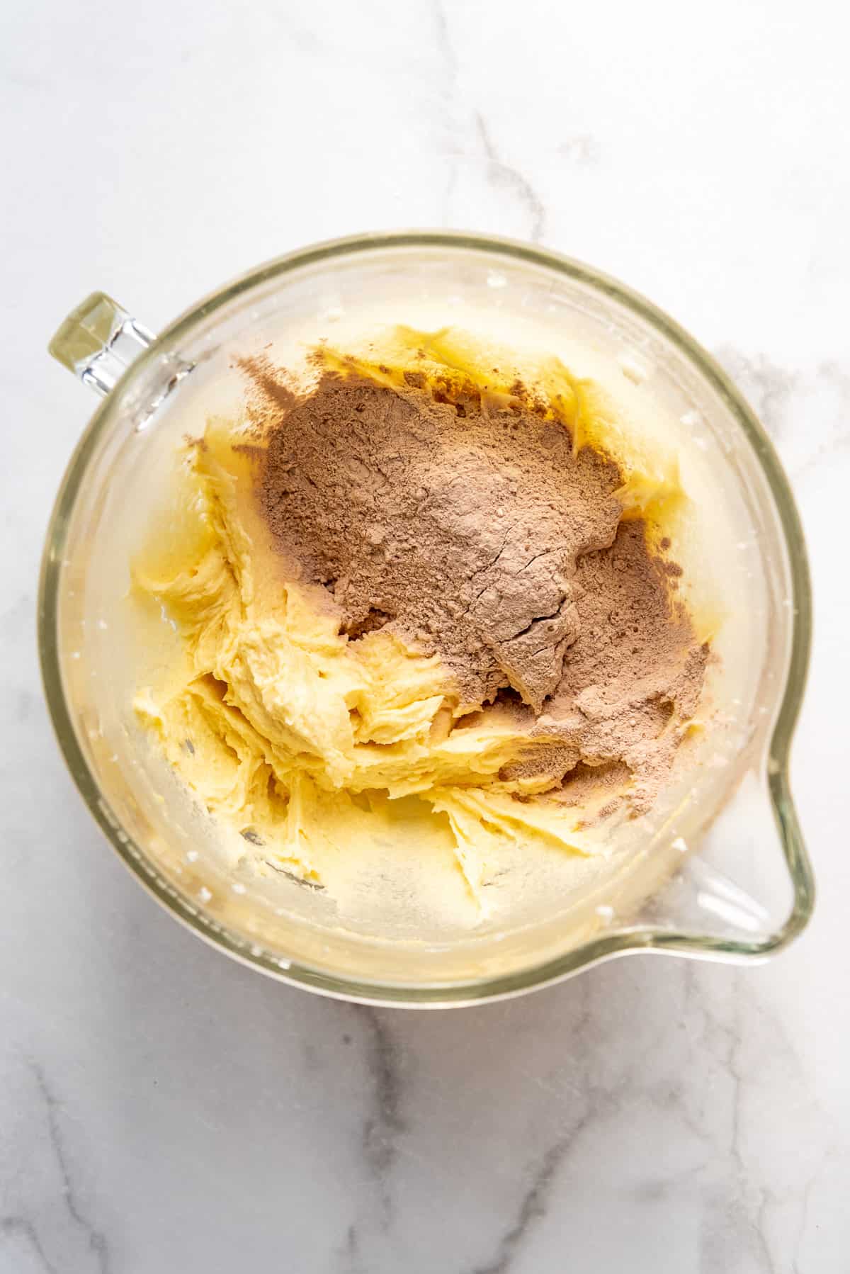 Adding dry ingredients to wet ingredients in a glass mixing bowl.