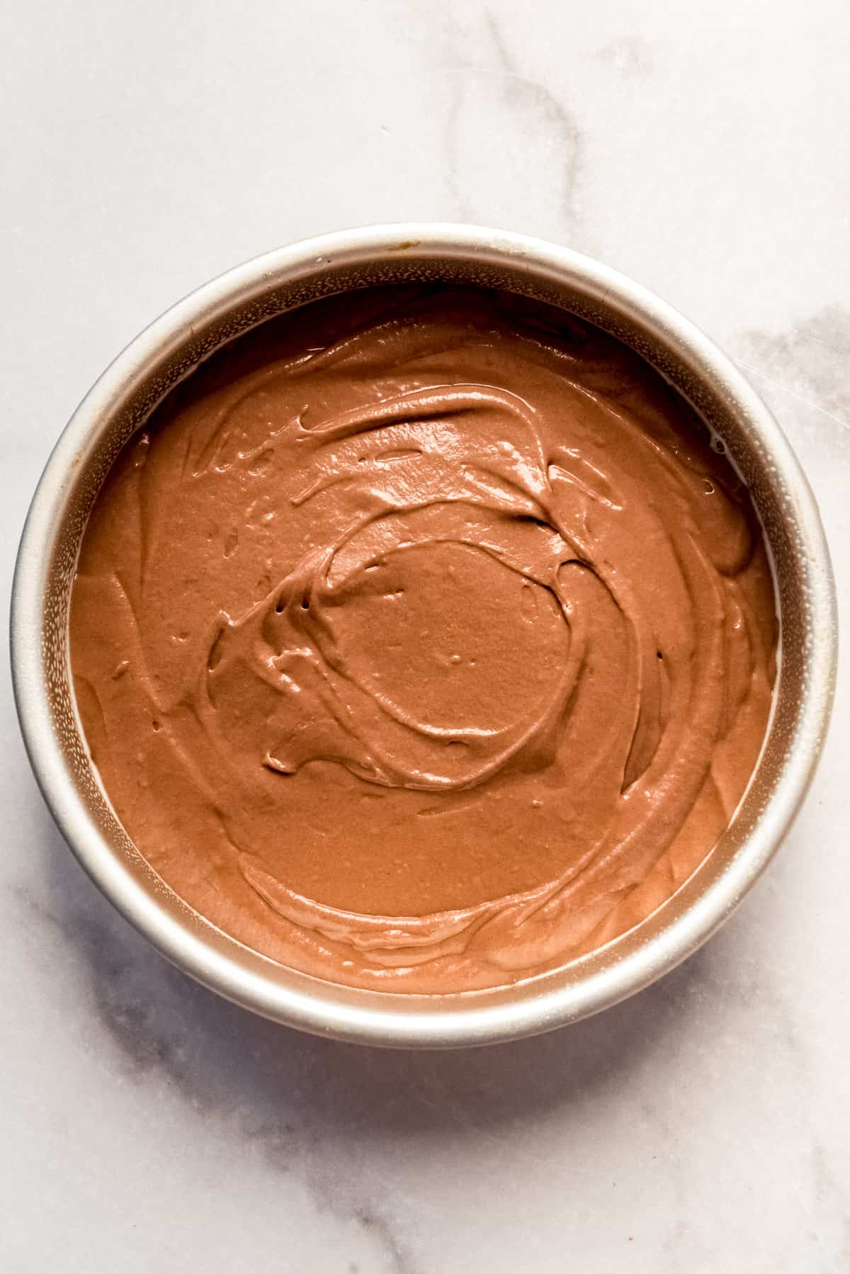 Spreading chocolate cake batter into a pan.