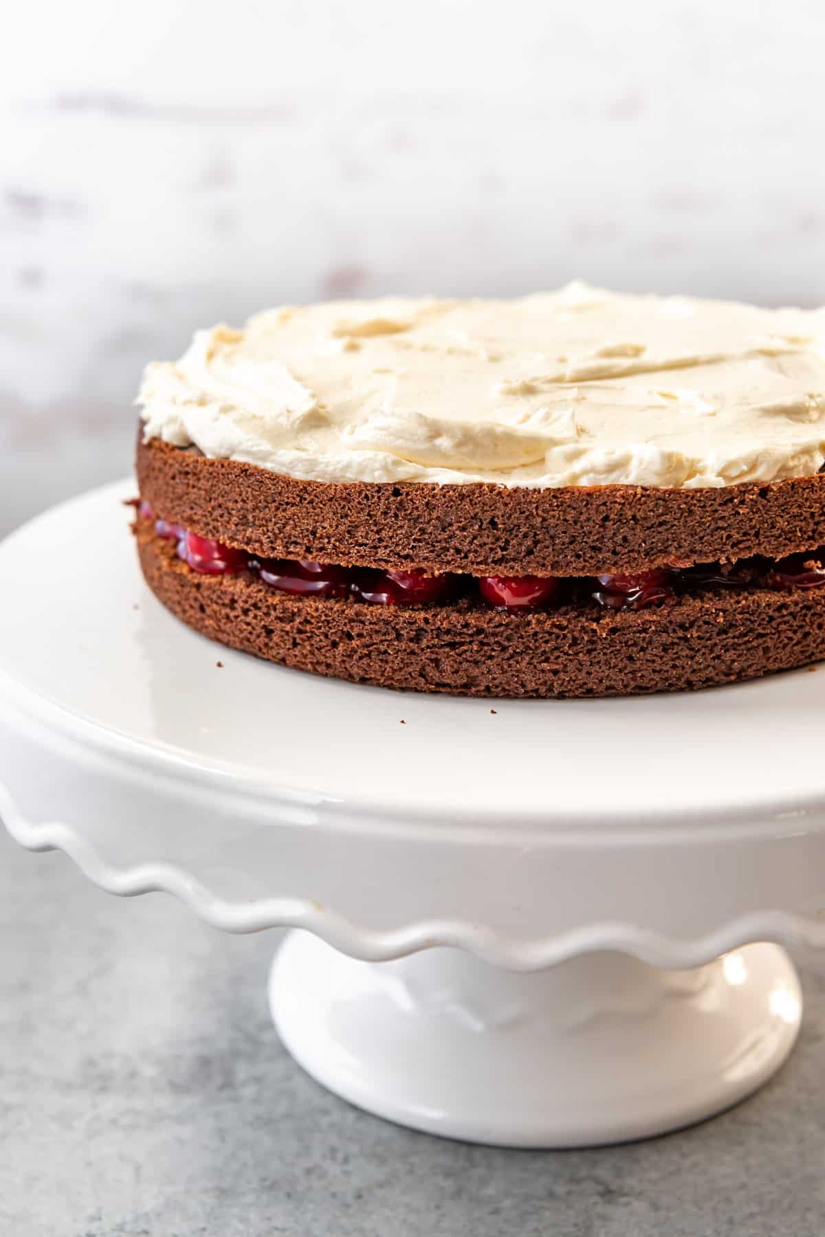 Assembling black forest cake with a layer of whipped ermine buttercream frosting.