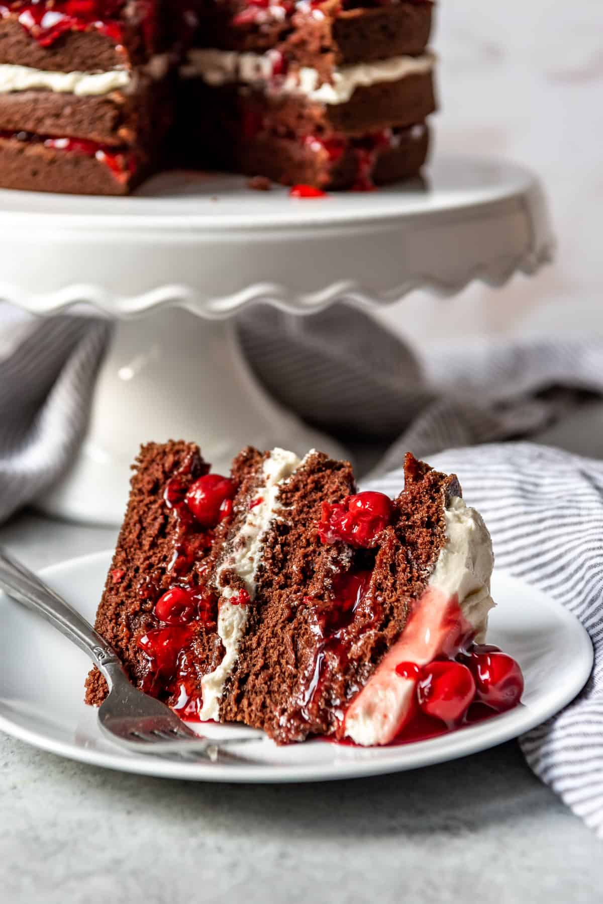 A slice of cherry chocolate Black Forest cake on a white plate with a fork.