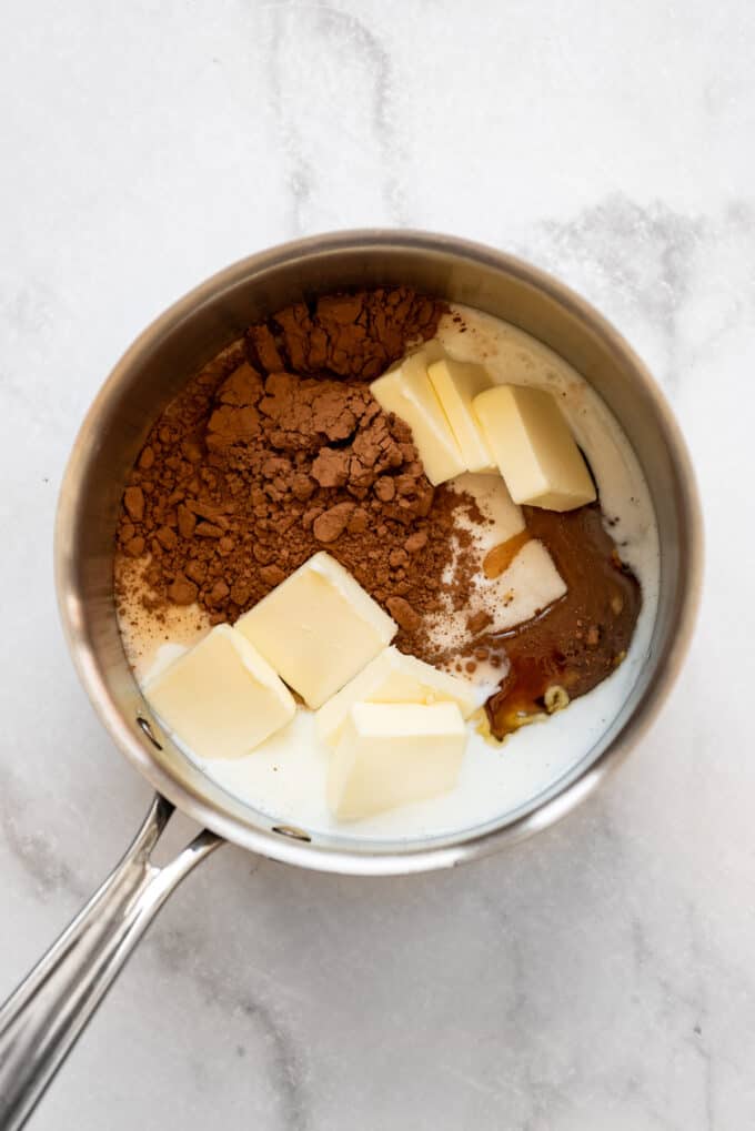 Combining cocoa powder, butter, sugar, and milk in a pot.
