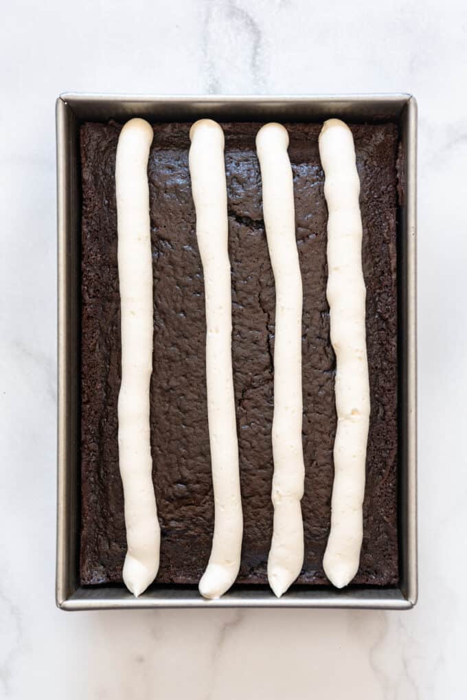 Four thick stripes of white frosting on a chocolate cake.