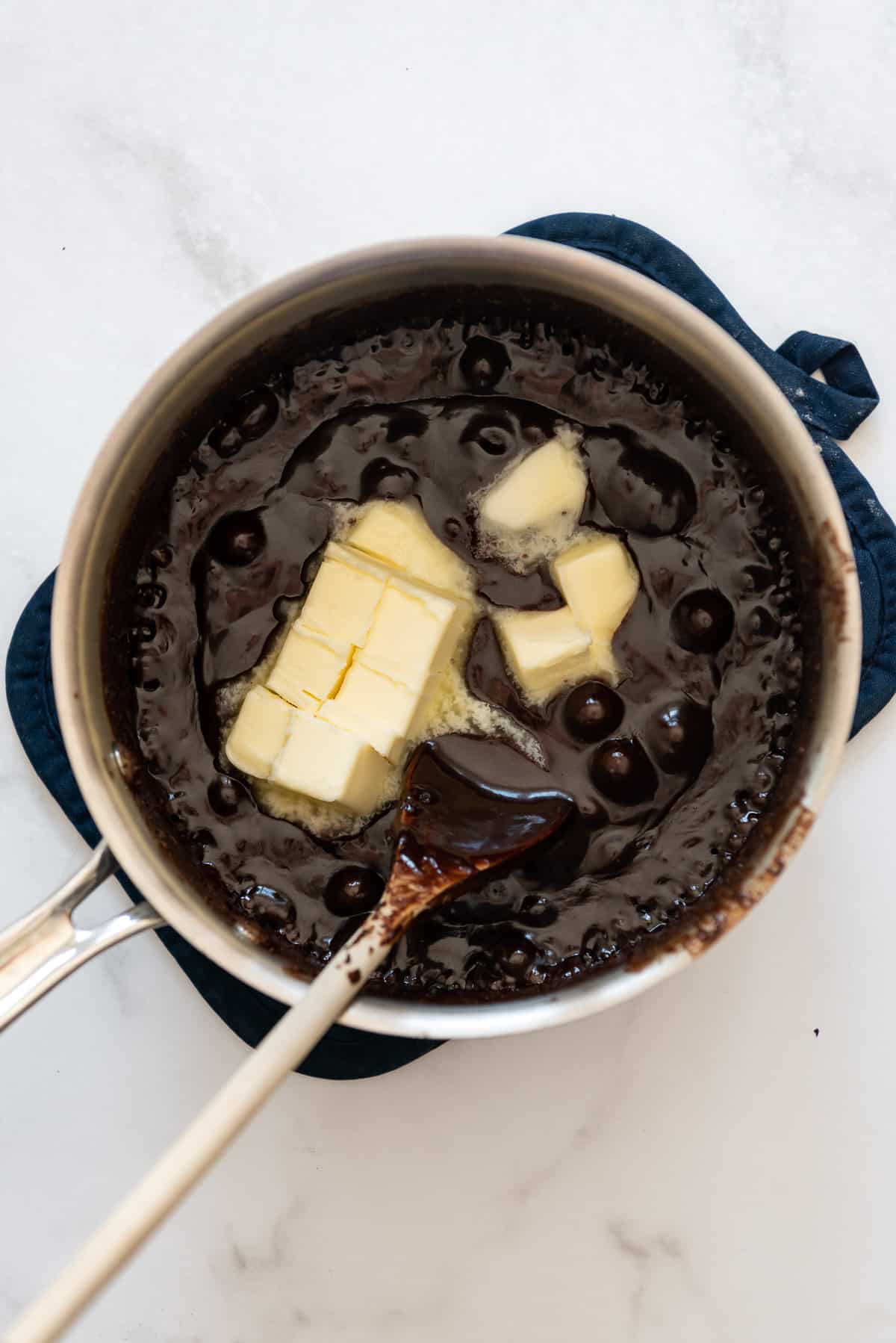 Adding cubed butter to cooked cocoa powder and sugar.