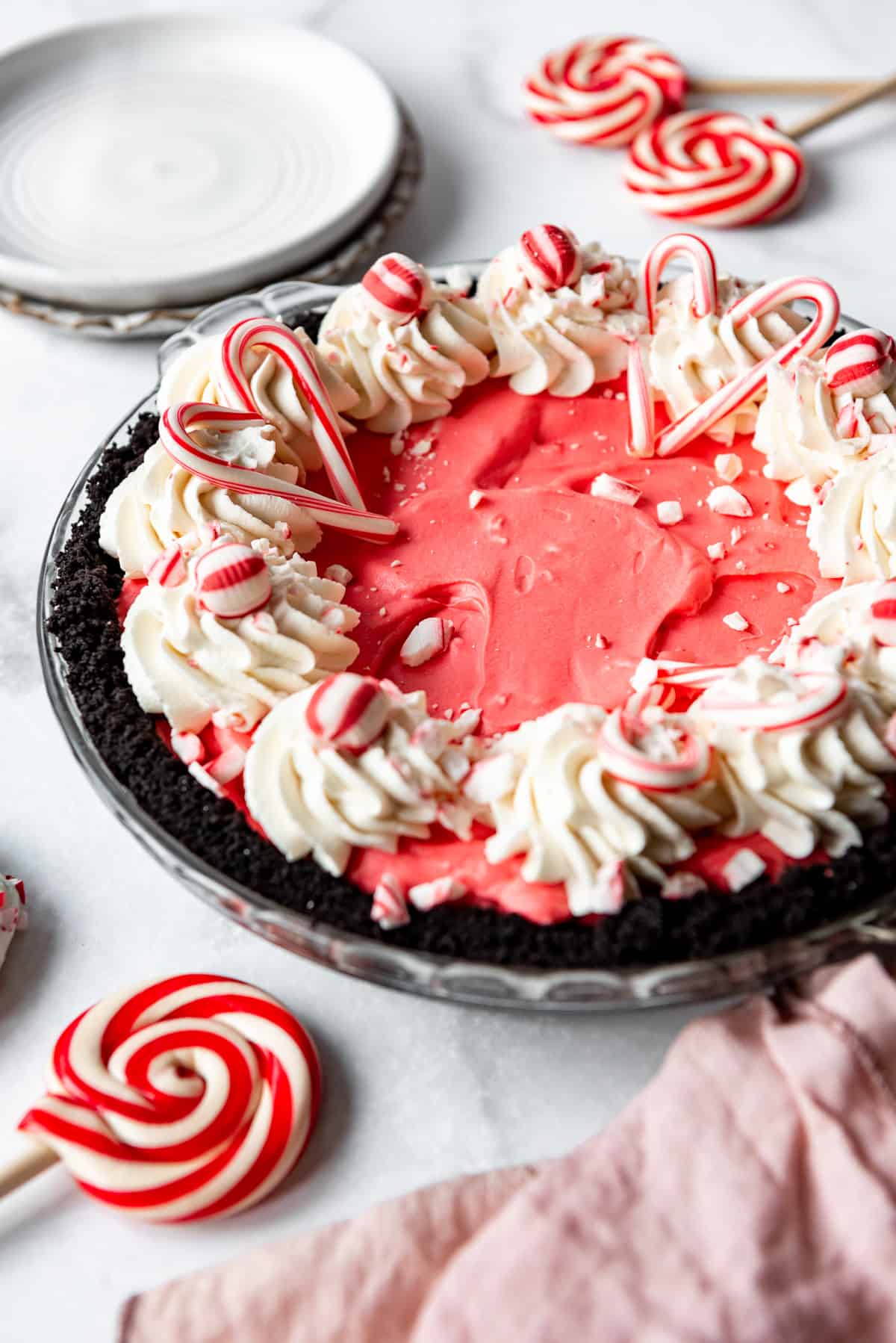 A no-bake peppermint cheesecake with an Oreo crust topped with whipped cream and candy canes.